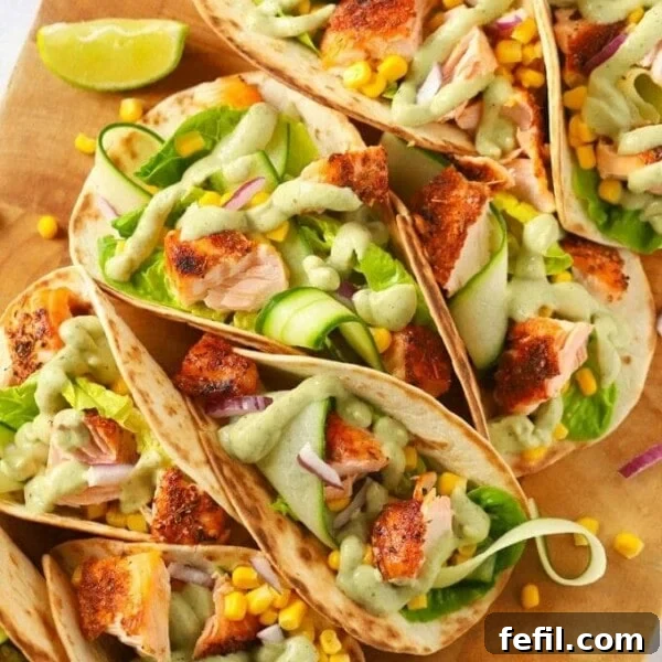 Easy salmon tacos recipe on a wooden board with cucumber and avocado dressing
