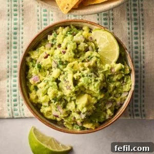 Fresh Guacamole Recipe: Zesty Homemade Mexican Dip 9 A bowl of homemade guacamole on a table with limes round the side.