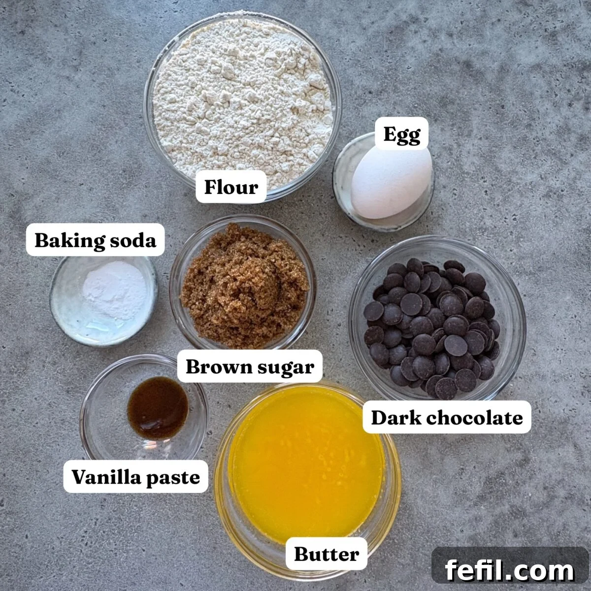 Gooey Chocolate Chip Skillet Cookie Recipe 5 Ingredients for Chocolate Chip Pizookie. Features bowls of melted butter, flour, vanilla paste, chocolate chips, baking soda, brown sugar, and an egg.