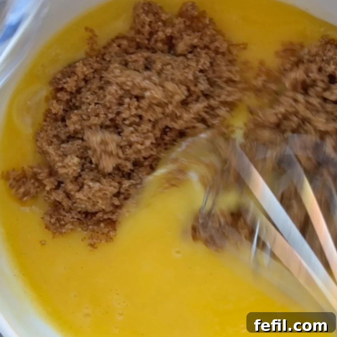 Gooey Chocolate Chip Skillet Cookie Recipe 6 Melted butter, vanilla paste, and light brown sugar being mixed in a bowl.