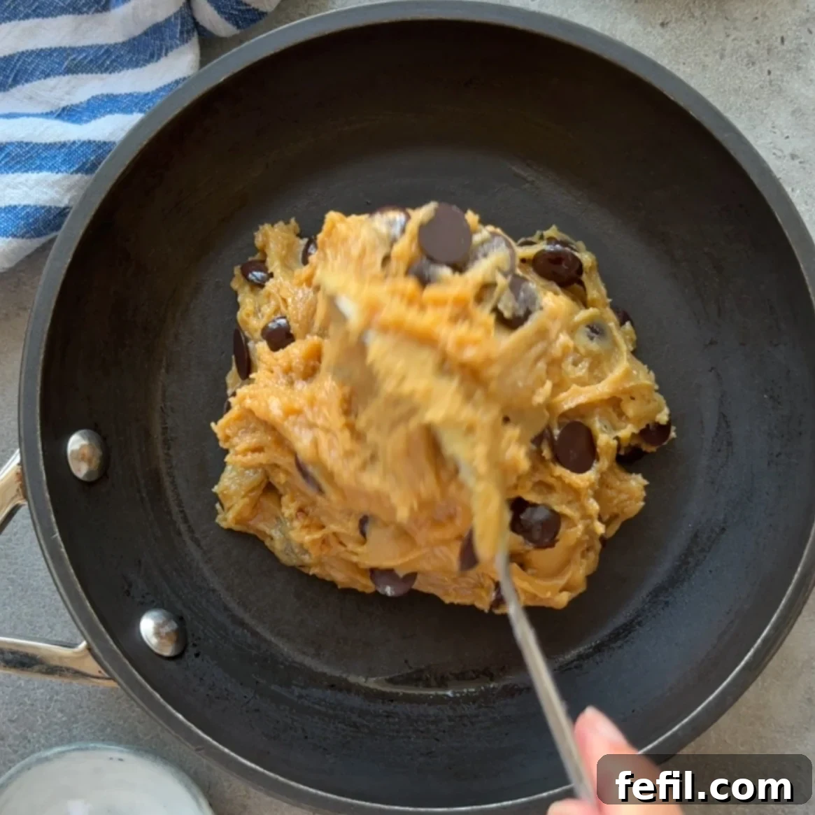 Gooey Chocolate Chip Skillet Cookie Recipe 8 Chocolate chip cookie dough is being spooned into a prepared skillet.