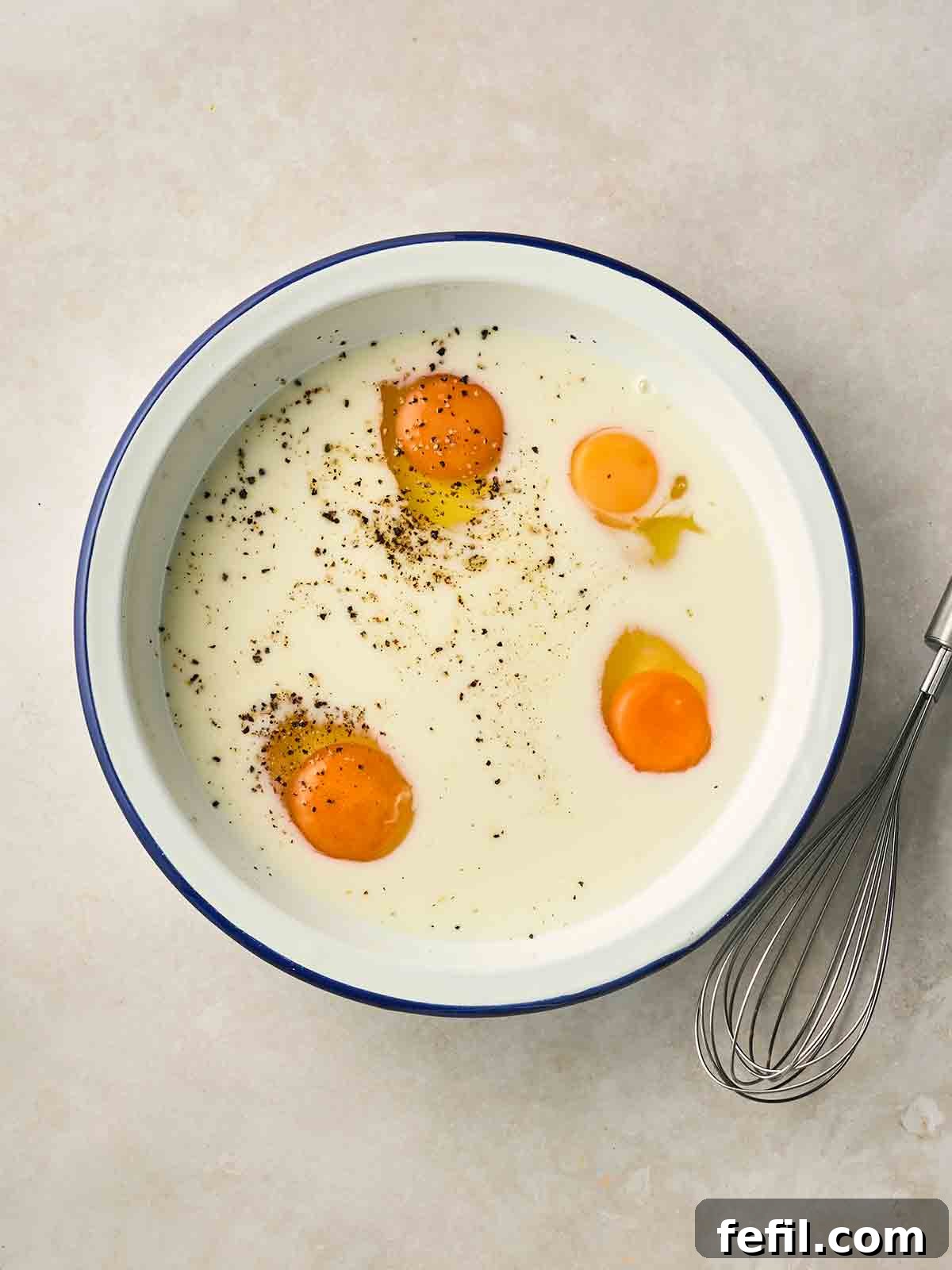 How to Make Classic Eggy Bread (British-Style French Toast) 5 Four eggs in a wide bowl with milk and salt and pepper.