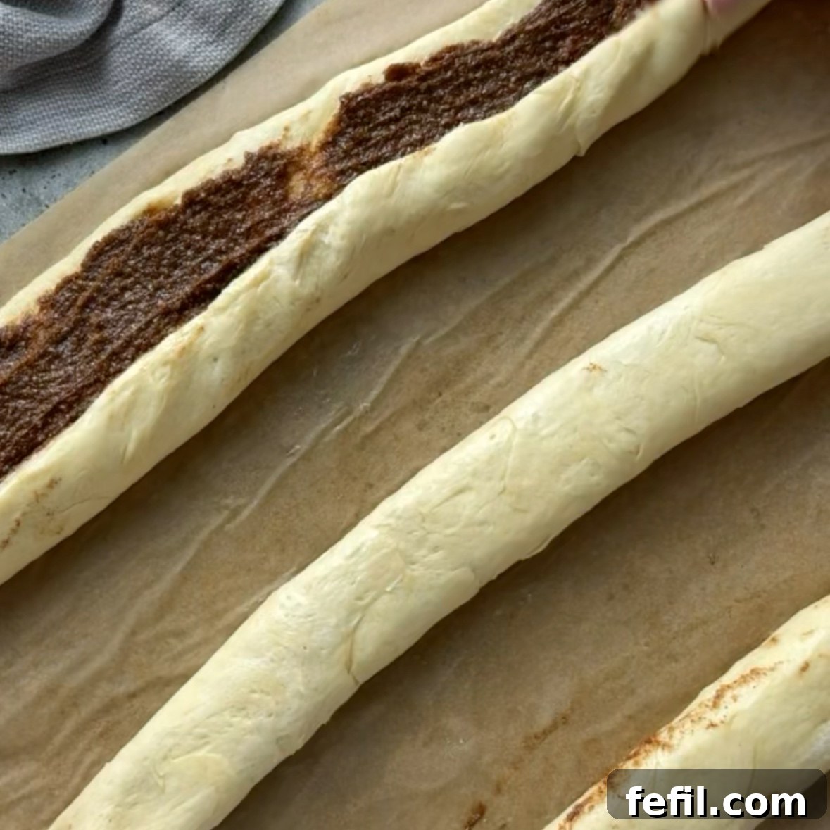 Mini Cinnamon Roll Bites with Cream Cheese Glaze 7 Three sections of cinnamon roll dough filled with brown sugar, butter, and cinnamon, are ready to be cut into rolls.