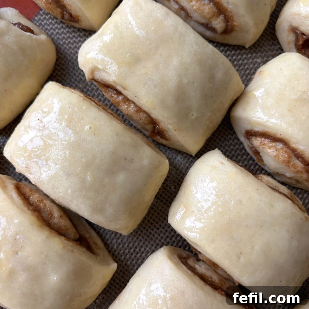 Mini Cinnamon Roll Bites with Cream Cheese Glaze 8 Proved mini cinnamon rolls brushed with egg wash, ready to be baked.