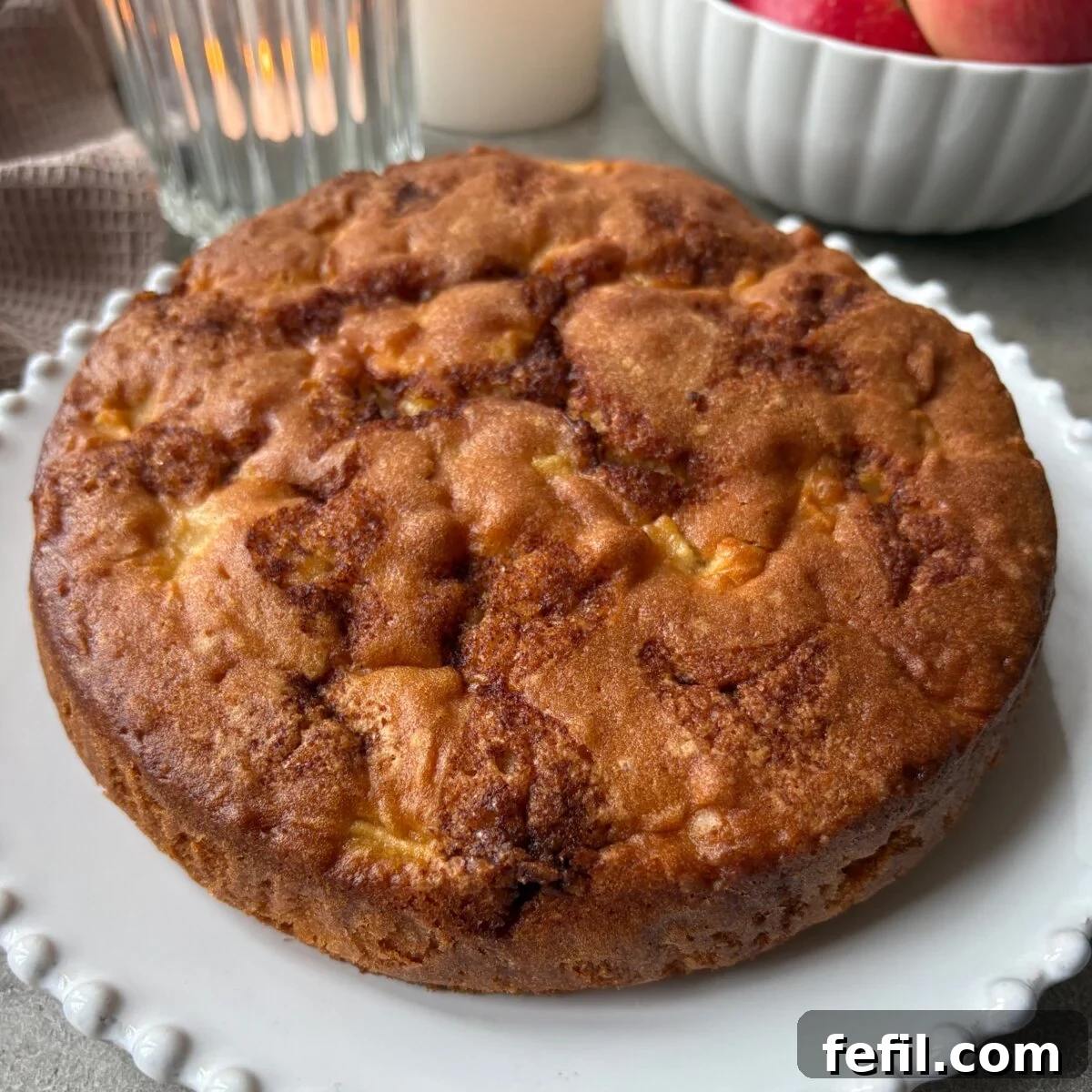 Classic Cinnamon Apple Cake with Warm Spice Glaze 2 A golden-baked Cinnamon Apple Cake on a white platter.