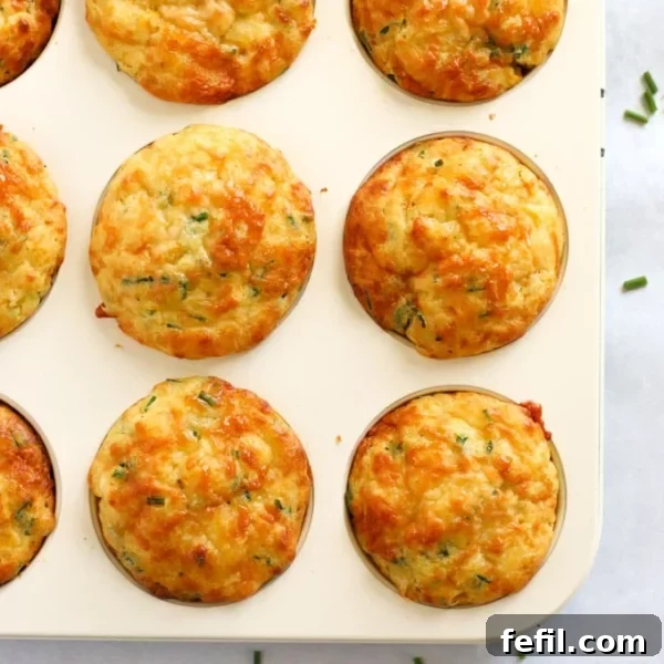Cheese and sweetcorn savoury muffins in a muffin tin, just baked and golden on top.