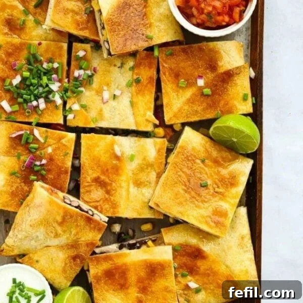 Sheet pan quesadillas cut into squares with lime and salsa.