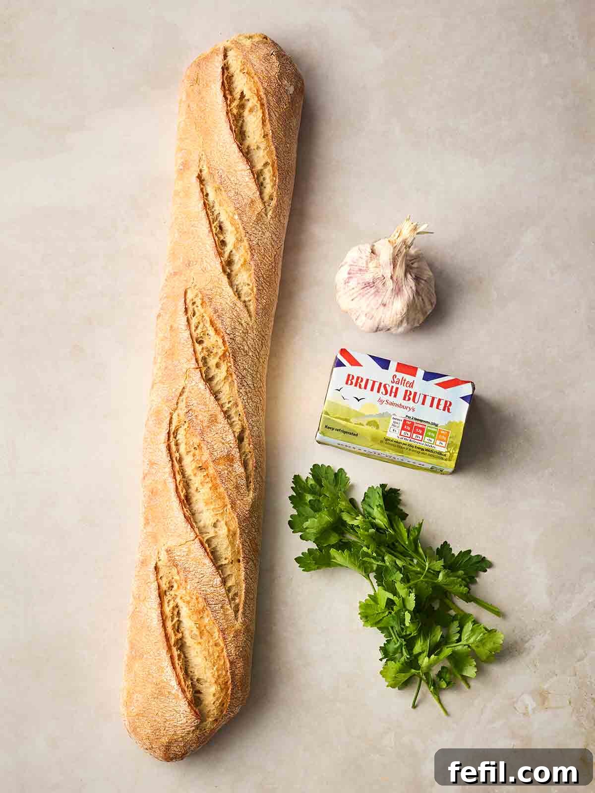 Perfect Crispy Garlic Bread with Herbed Butter 4 The ingredients for making Homemade Garlic Bread laid out on a white counter.
