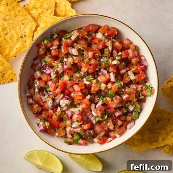 Perfect Crispy Garlic Bread with Herbed Butter 7 A bowl filled with fresh Salsa, with tortilla chips and lime wedges on the surface to the side.
