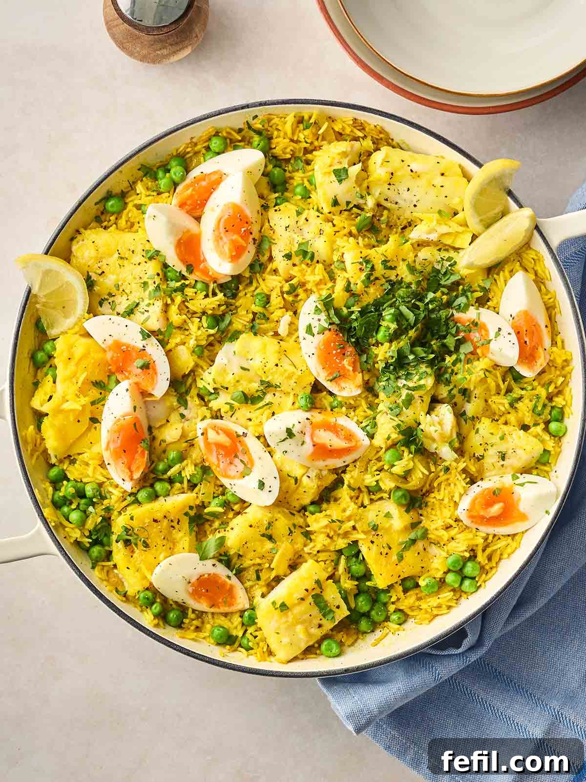Classic Kedgeree: Smoked Fish, Rice & Curried Eggs 2 A large pan of Kedgeree with fish, rice and boiled eggs, garnished with lemon wedges and parsley, on a table, ready to serve.