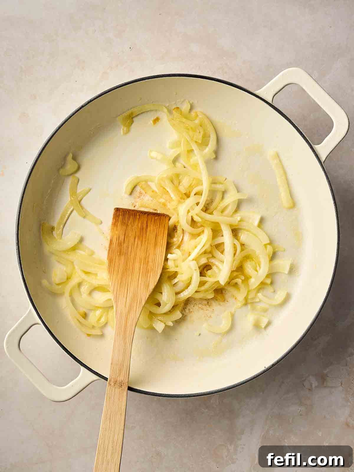 Classic Kedgeree: Smoked Fish, Rice & Curried Eggs 6 A pan of sliced onions, frying with a wooden spatula in.