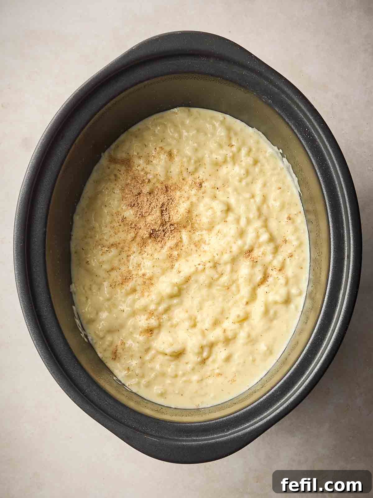 Creamy Slow Cooker Rice Pudding Recipe 2 A slow cooker pan with cooked rice pudding inside.
