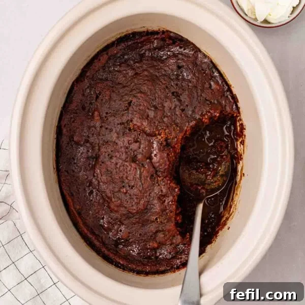 Creamy Slow Cooker Rice Pudding Recipe 9 A slow cooker with cooked Sticky Toffee Pudding inside, with a sauce under the sponge. A spoon to serve up.