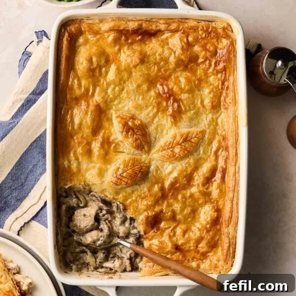 A pie with chicken and mushroom filing on a table, being served with a spoon.