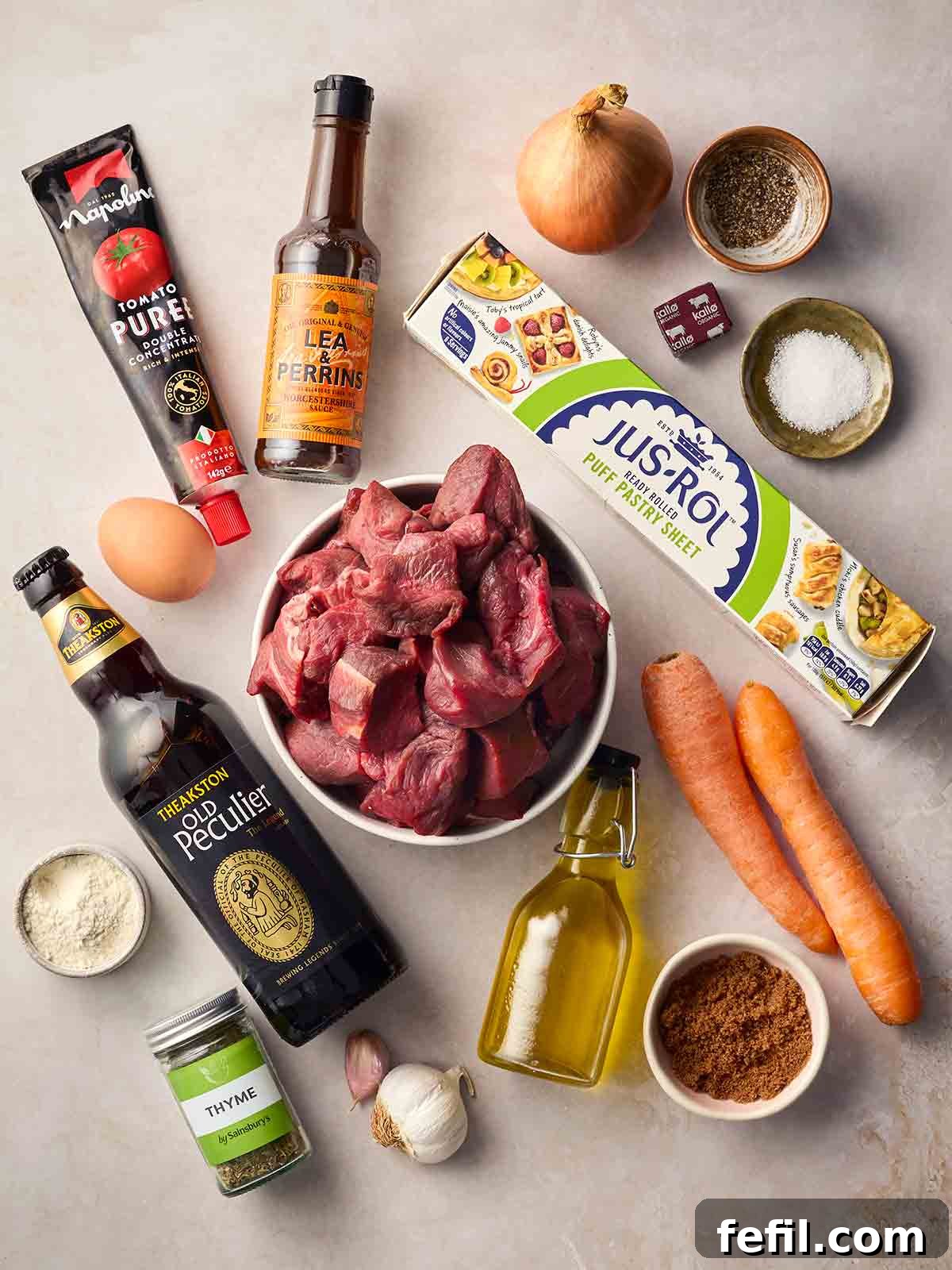 The ingredients for making Steak and Ale Pie all laid out on a white surface.
