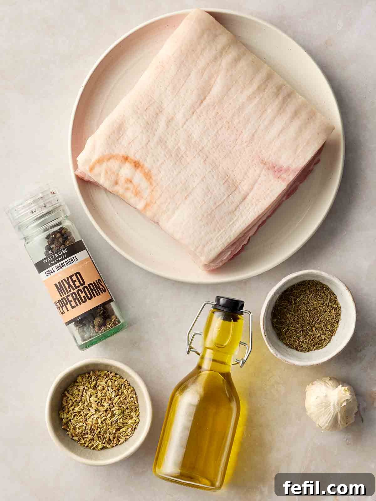How to Make Crispy Pork Belly with Perfect Crackling Skin 4 The ingredients for making roast pork belly with crackling laid out on a white surface.