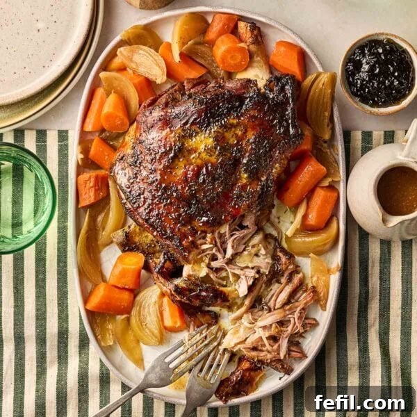 How to Make Crispy Pork Belly with Perfect Crackling Skin 8 A cooked lamb shoulder joint on a platter with onions and carrots, on a set dining table, ready to be dished up.